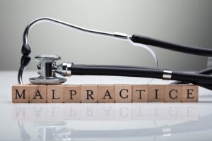 a stethoscope on a row of letter blocks spelling "malpractice"
